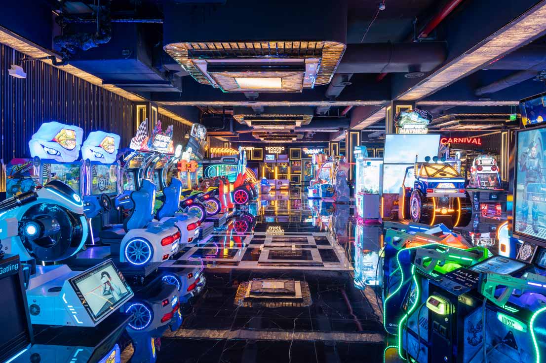 Group of friends laughing and playing air hockey and racing arcade games at The Game Palacio